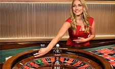 Casino virtual en vivo con una crupier detrás de una ruleta.