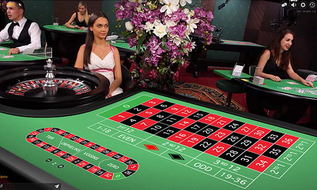 Sala de casino con varias mesas de juegos y crupieres
