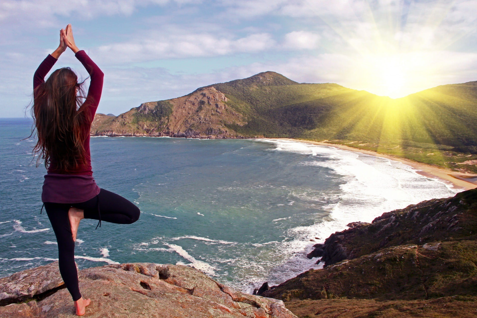 Una mujer que hace ejercicio de yoga mirando el sol.