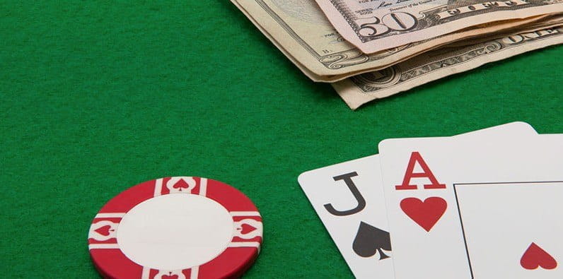Una mesa de casino con dinero en efectivo y dos cartas: un as y una jota
