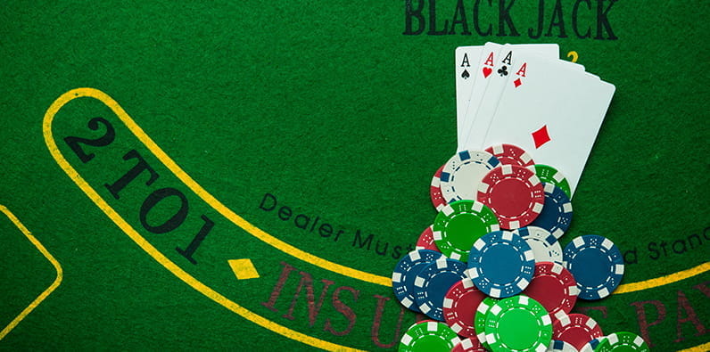 Una mesa de blackjack con fichas de casino y cuatro cartas de ases. 
