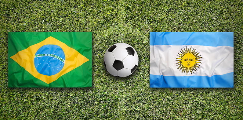 Un balón de fútbol entre las banderas nacionales de Brasil y Argentina