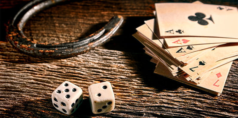 Una herradura, cartas de juego y dados en una mesa.