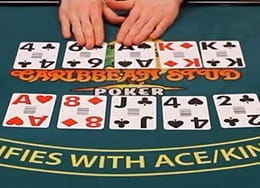 Mesa de casino en la que se ven cartas de póker en vivo y las manos del crupier.