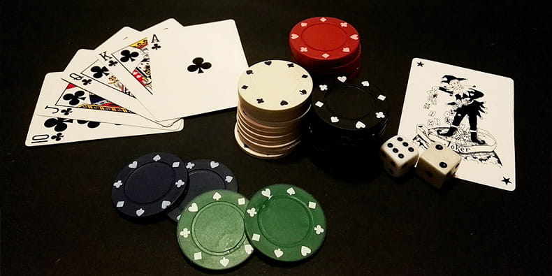 Varias cartas, fichas y dados de casino sobre un tapete. 