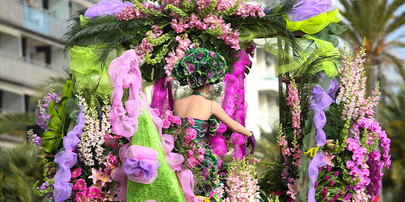 Foto de la Batalla de las Flores de Jersey. Hay varios aviones hechos con flores rojas y blancas, y niños saludando.