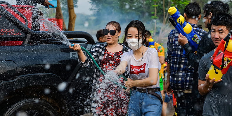 Foto de la fiesta del agua de Songkran. Varias personas asiáticas juegan con mangueras y pistolas de agua.