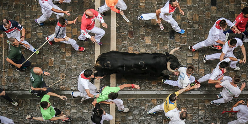 Foto del Encierro de San Fermín. Un toro negro corre suelto junto a los participantes de la fiesta.