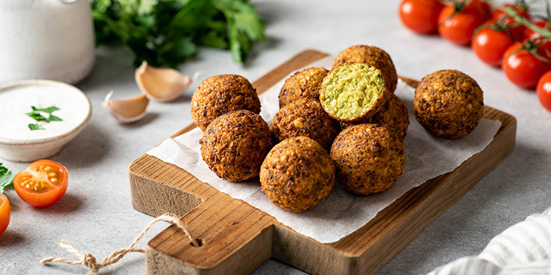 Diferentes piezas de falafel redondas y perfectamente cocinadas en primer plano, dispuestas sobre un plato. 