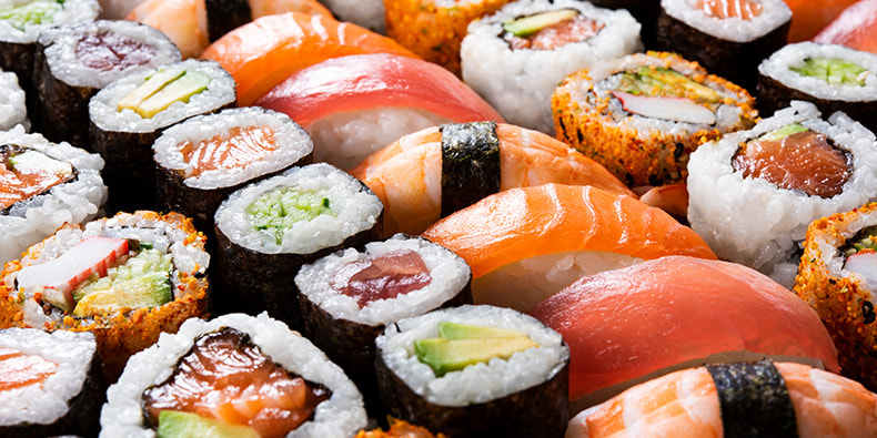 Un plato con variedad de sushi con salmón, aguacate, arroz y otros ingredientes, presentados sobre una tabla de madera.