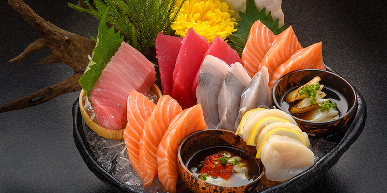 Una presentación artística de diferentes tipos de sashimi con cortes variados y una disposición hermosa. 